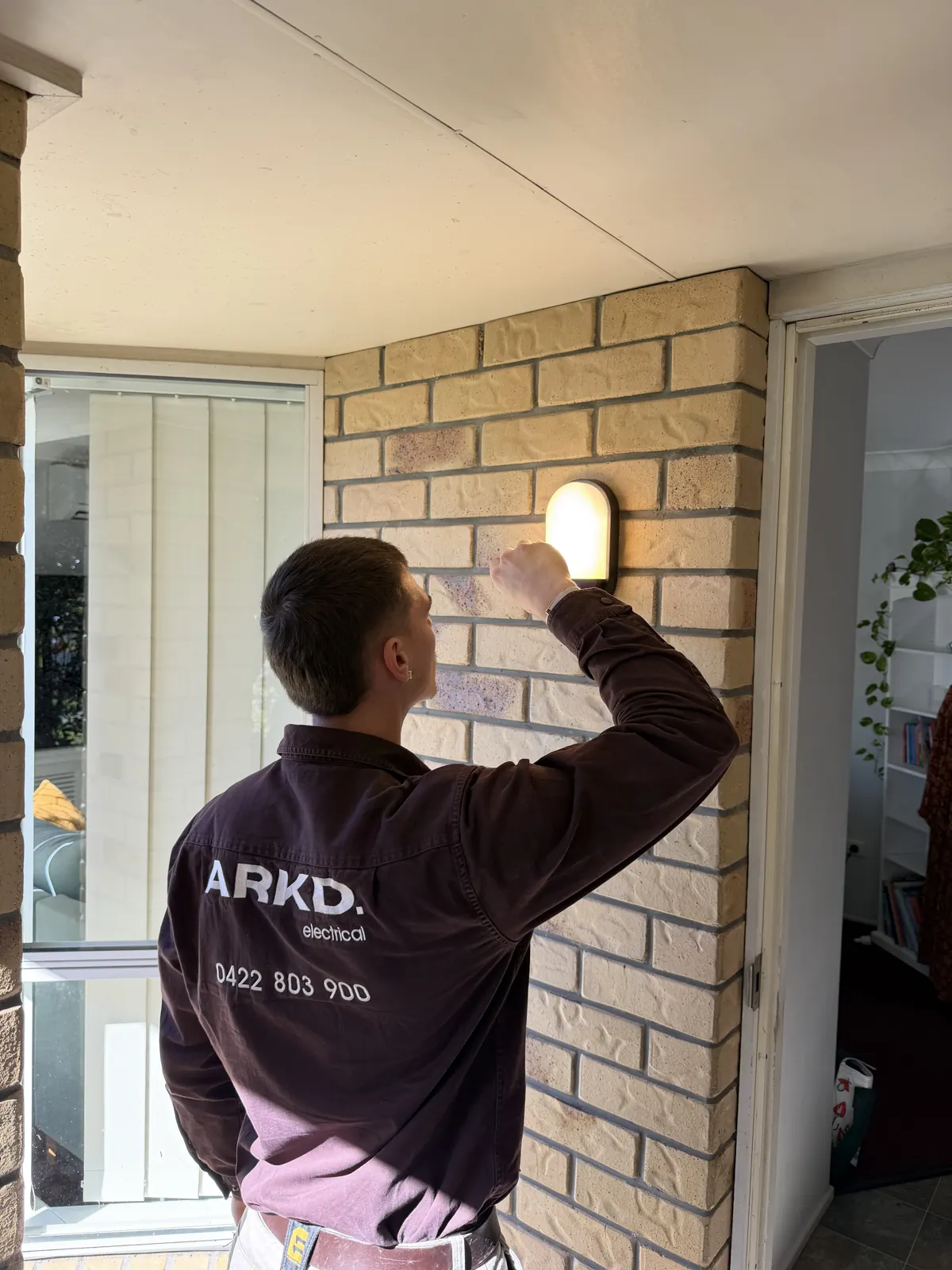 ARKD electrician servicing an exterior wall light at a Brisbane residence