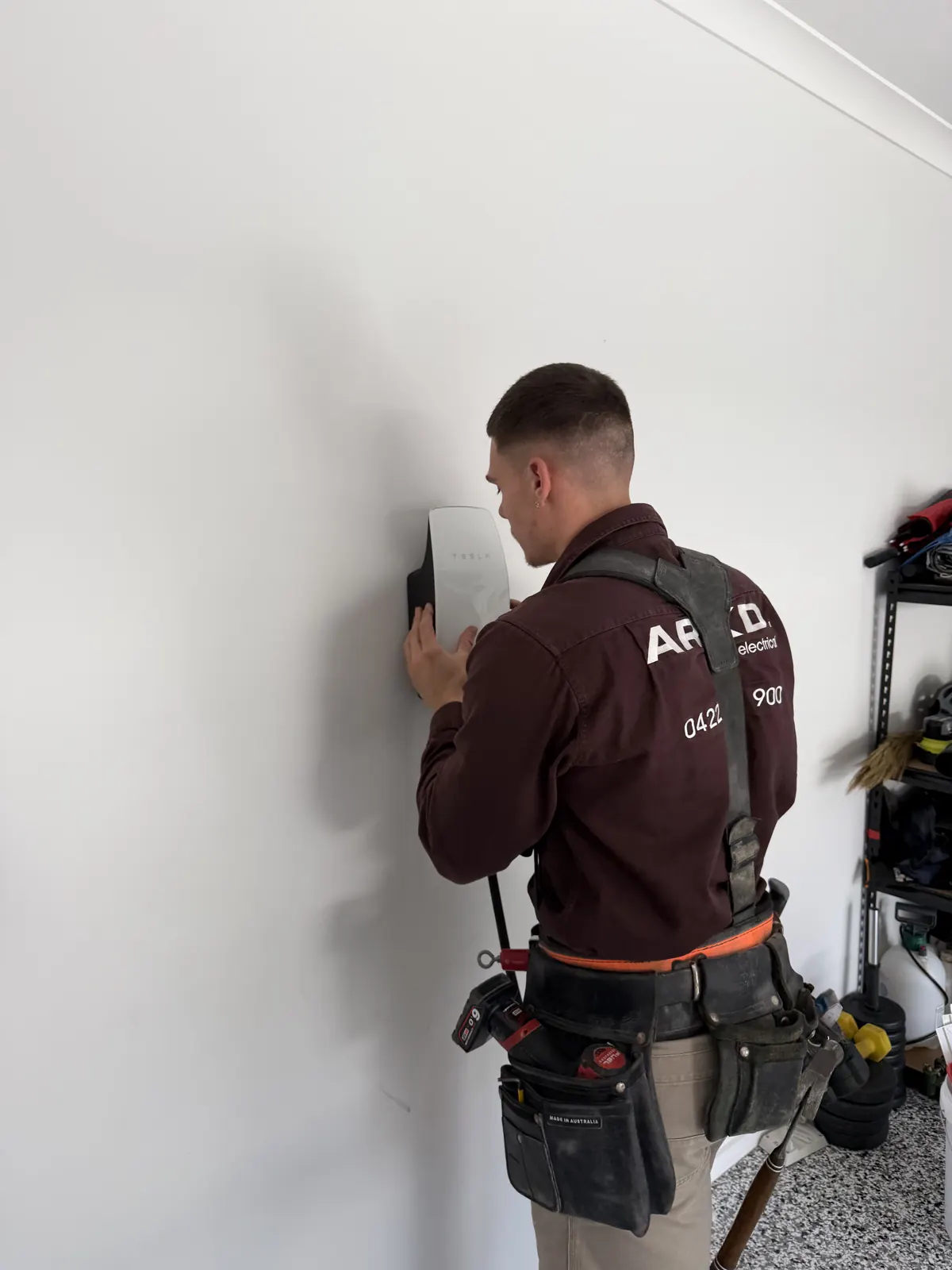 ARKD electrician installing a Tesla Wall Connector EV charger in a Brisbane garage